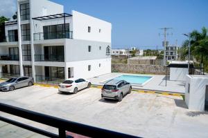 dos autos estacionados en un estacionamiento frente a un edificio en “Hermoso Apartamento En Bávaro” en Punta Cana
