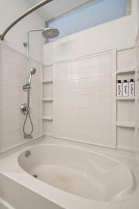La salle de bains est pourvue d'une baignoire et de carrelage blanc. dans l'établissement CozySuites Mill District pool gym # 05, à Minneapolis