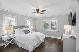 a white bedroom with a bed and a ceiling fan at Forest Hills Cottage in Augusta