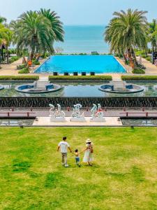 una famiglia che cammina sull'erba di fronte a una piscina di DoubleTree by Hilton Shanwei a Shanwei
