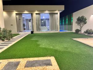a yard with green grass in front of a house at شاليه جود in Riyadh
