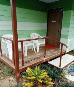 a porch with two white chairs and a table at Papa Camping Home and Bungalows in Thalang