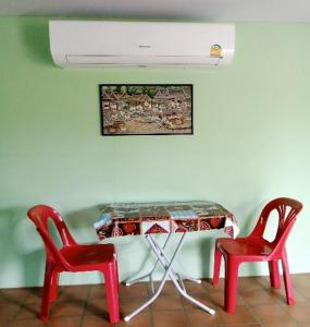 a table with two red chairs and a white ceiling at Papa Camping Home and Bungalows in Thalang