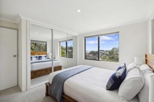 ein Schlafzimmer mit einem großen Bett und zwei Fenstern in der Unterkunft Little Gem in Coffs Harbour