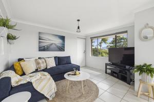 ein Wohnzimmer mit einem blauen Sofa und einem TV in der Unterkunft Little Gem in Coffs Harbour