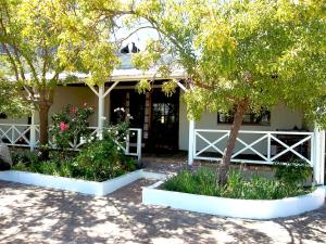 a white house with trees and flowers in front of it at La Verdure Fruit Farm in Franschhoek