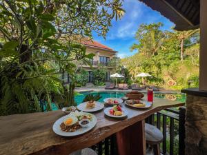 a table with food on it next to a pool at The Mudru Resort by Pramana Villas in Ubud