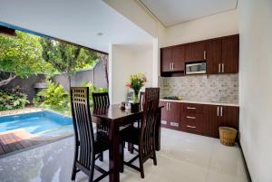 a kitchen with a table and chairs and a swimming pool at Gracia Bali Villas & Apartment by Manara in Seminyak