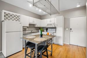 a kitchen with white cabinets and a table and chairs at CozySuites Mill District with pool, gym #06 in Minneapolis