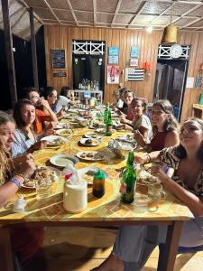 Sera Beach Dive Resort في Kododa: مجموعة من الناس يجلسون على طاولة يأكلون الطعام