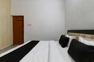 uma cama com lençóis e almofadas preto e branco em OYO Flagship Dripp Stay Inn em Lucknow