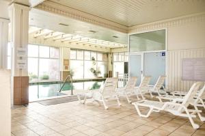 Habitación con sillas blancas y piscina en Hippocampus resort en Concón