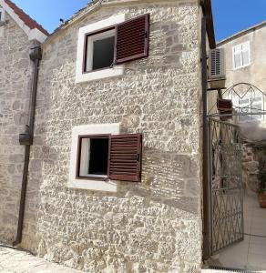 two windows on a stone building with brown shutters at Secret House Andrea in Primošten