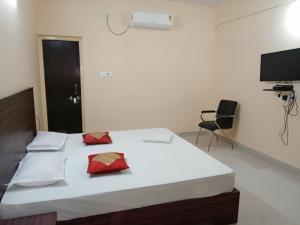 a bedroom with a large white bed with red pillows at Goroomgo Green Akress Bhubaneswar in Bhubaneshwar