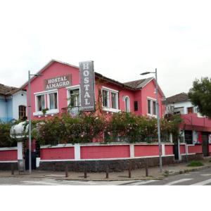 a pink building with a sign in front of it at Hostal Almagro in Quito