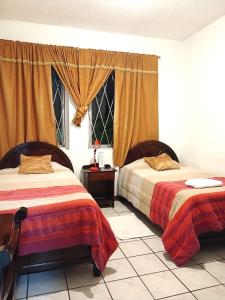 a bedroom with two beds and a window at Hostal Almagro in Quito