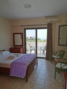 a bedroom with a bed and a balcony with chairs at Nefeli Apartments in Stoupa