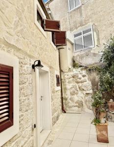 a stone house with a white door and a sidewalk at Secret House Andrea in Primošten