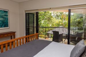 een slaapkamer met een bed en een balkon bij Eden Retreat - Port Douglas in Port Douglas