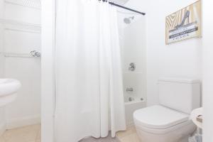 La salle de bains blanche est pourvue de toilettes et d'un rideau de douche. dans l'établissement Home Miami Downtown with Balcony - 5 minutes from Wynwood & Port - Art District near Beach, à Miami