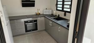 a kitchen with gray cabinets and a sink and a microwave at Paradise City Break in Saint-Pierre