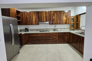 a kitchen with wooden cabinets and a stainless steel refrigerator at La Casa de Beto in La Manzanilla