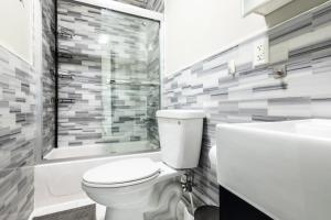 Spacious 4BD Gem in Manhattan في نيويورك: حمام مع مرحاض وحوض استحمام ومغسلة