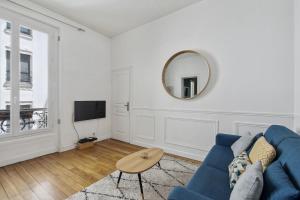 een woonkamer met een blauwe bank en een spiegel bij Le Marais & Arts et Métiers - CityApartmentStay in Parijs