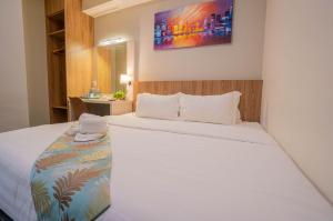 FLYPOD Hotel في كوتا كينابالو: غرفة نوم بسرير ابيض ومغسلة
