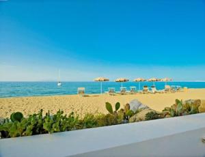 uma praia com guarda-sóis e cadeiras e o oceano em Ancora Bianca Beach Residence em Terme Vigliatore