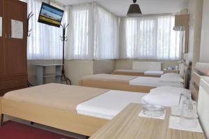 a hotel room with three beds and a television at Otel Sınal in Kocaeli