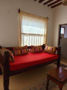 ein rotes Sofa im Wohnzimmer mit Fenster in der Unterkunft Happiness House in Shela