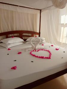 un lit avec deux cygnes en rosiers dans l'établissement Happiness House, à Shela