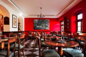 a restaurant with red walls and wooden tables and chairs at Sebnitzer Hof by STEIGER Hotels in Bad Schandau