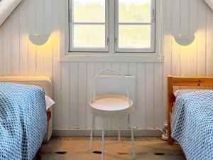リンケビングにあるHoliday Home Strandgårdsvej IIIのベッド2台が備わる客室で、椅子が備わります。