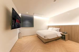 a bedroom with a large white bed and a television at Hound Hotel Jeonju Deokjin in Jeonju