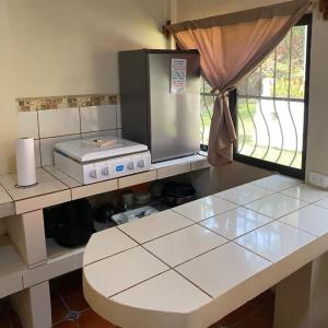 a kitchen with a counter top with a refrigerator at Arcadia Cabañas Vacacionales in Retalhuleu