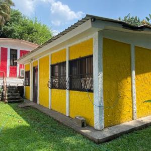 a yellow building with a balcony in a yard at Arcadia Cabañas Vacacionales in Retalhuleu