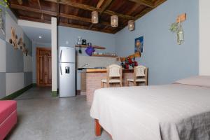 a bedroom with a white bed and a kitchen at Nopalero Suites Hostel in Puerto Escondido