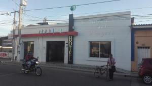 dos personas en bicicleta en la calle frente a un edificio en Hotel La Nueva Casa del viajero, en Aguachica