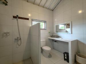 La salle de bains est pourvue de toilettes, d'un lavabo et d'une douche. dans l'établissement Alam Cottage Uluwatu, à Uluwatu