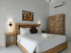 a bedroom with a large white bed with two dolls on it at Alam Cottage Uluwatu in Uluwatu