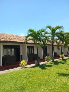 a house with palm trees in front of a yard at Ceylonica Beach Hotel in Negombo