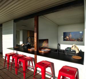 a kitchen with red stools and a counter with a sink at DUENDE Sirène Mermaid in Midgeton