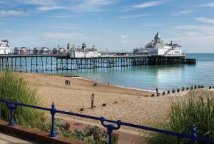 a pier with people walking on the beach near the water at Cosy, Modern One Bedroom Apartment, Close to Train, City, Beach and Hospital Long Booking Welcome in Eastbourne