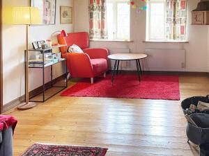 ein Wohnzimmer mit einem roten Stuhl und einem Tisch in der Unterkunft Holiday home Löderup III in Löderup