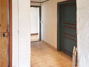 ein leeres Zimmer mit grüner Tür und Holzboden in der Unterkunft Holiday home Löderup III in Löderup