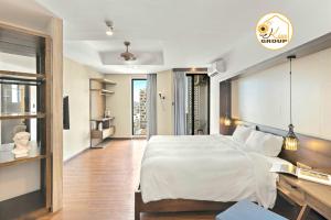 a bedroom with a large white bed and a desk at Tokyo Boutique Front Beach Hotel in Danang