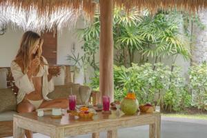 a woman sitting on a couch talking on a cell phone at Oasis Bungalows in Uluwatu