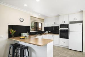a kitchen with white cabinets and a wooden counter top at Lakeside Country Club in Numurkah